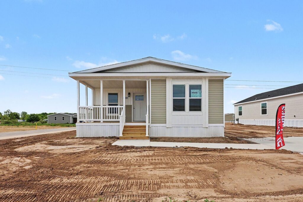 Front porch of a new manufactured home with tan siding and white railings at 4140 Shalimar Dr in Allendale, MI