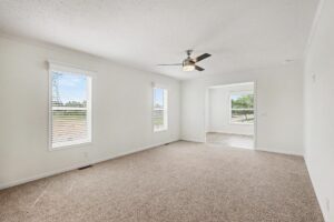 Carpeted living room with ceiling fan and two windows in a new manufactured home at 4140 Shalimar Dr in Allendale, MI