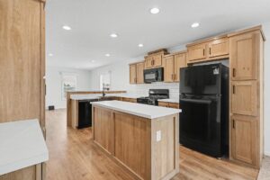 Kitchen island and pantry cabinets with black refrigerator in a new manufactured home at 4140 Shalimar Dr in Allendale, MI