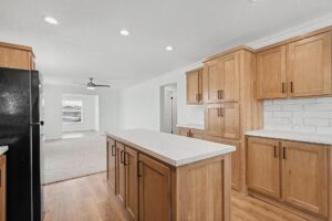 Kitchen island with white countertop and oak cabinets in a new manufactured home at 4140 Shalimar Dr in Allendale, MI