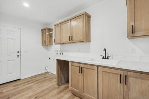Laundry room with oak cabinets and utility sink in a new manufactured home at 4140 Shalimar Dr in Allendale, MI