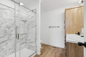 Bathroom with glass walk-in shower and marble-look tile in a new manufactured home at 4140 Shalimar Dr in Allendale, MI