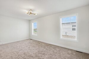 Carpeted bedroom with pendant light and two windows in a new manufactured home at 4152 Shalimar Dr in Allendale, MI