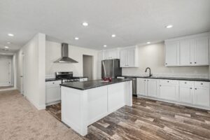 White kitchen with dark countertops, island and stainless appliances in a new manufactured home at 4152 Shalimar Dr in Allendale, MI