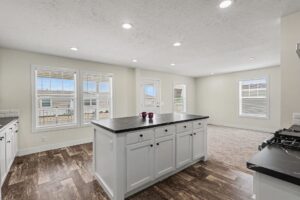 Kitchen island with dark countertop and three windows in a new manufactured home at 4152 Shalimar Dr in Allendale, MI