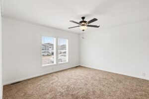Carpeted living room with ceiling fan and windows in a new manufactured home at 4159 Shalimar Dr in Allendale, MI