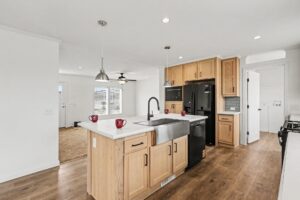 Kitchen with oak cabinets, farmhouse sink and black appliances in a new manufactured home at 4159 Shalimar Dr in Allendale, MI