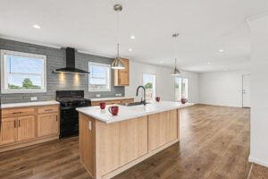 Kitchen with slate tile backsplash, oak cabinets and island in a new manufactured home at 4159 Shalimar Dr in Allendale, MI