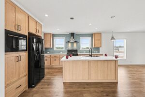 Kitchen island with pendant lights and black wall oven in a new manufactured home at 4159 Shalimar Dr in Allendale, MI
