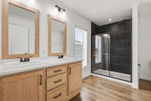 Bathroom with oak double vanity and dark tile shower in a new manufactured home at 4159 Shalimar Dr in Allendale, MI