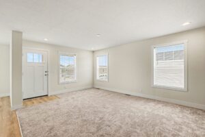 Carpeted living room with front door and windows in a new manufactured home at 4160 Shalimar Dr in Allendale, MI