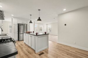 White kitchen with island, pendant lights and stainless appliances in a new manufactured home at 4160 Shalimar Dr in Allendale, MI