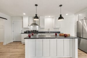 Kitchen island with dark countertop and pendant lights in a new manufactured home at 4160 Shalimar Dr in Allendale, MI