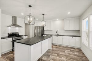White kitchen with range hood, island and dark countertops in a new manufactured home at 4180 Shalimar Dr in Allendale, MI
