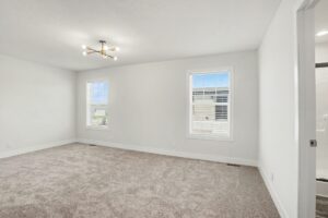 Carpeted bedroom with light fixture and two windows in a new manufactured home at 4180 Shalimar Dr in Allendale, MI