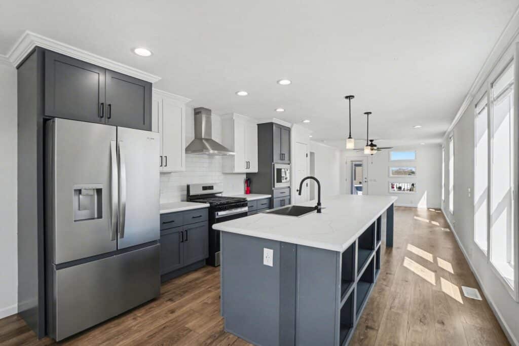 Kitchen with stainless refrigerator and gray island in a new manufactured home at 4198 Shalimar Dr