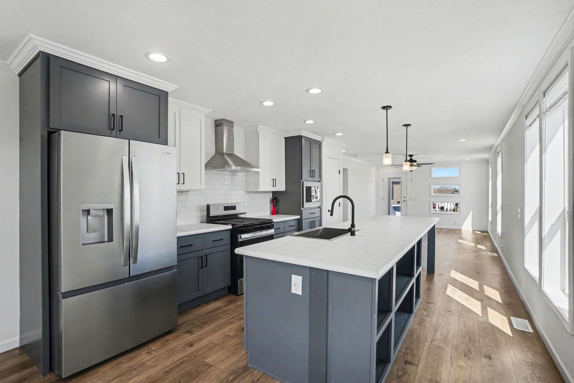 Kitchen with stainless refrigerator and gray island in a new manufactured home at 4198 Shalimar Dr in Allendale, MI