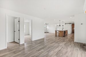 Open living room with wood-look flooring and kitchen island in a new manufactured home at 4201 Shalimar Dr in Allendale, MI