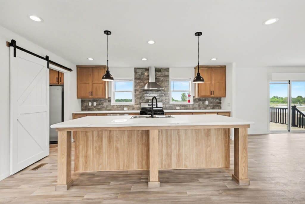 Kitchen island with pendant lights and barn door pantry in a new manufactured home at 4201 Shalimar Dr