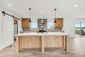 Kitchen island with pendant lights and barn door pantry in a new manufactured home at 4201 Shalimar Dr in Allendale, MI