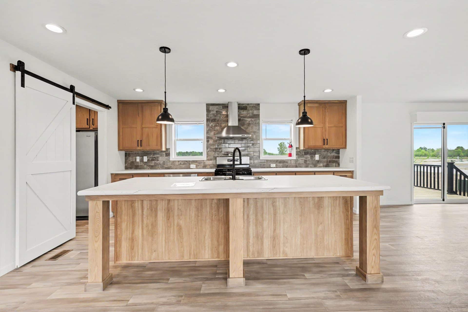 Kitchen island with pendant lights and barn door pantry in a new manufactured home at 4201 Shalimar Dr in Allendale, MI
