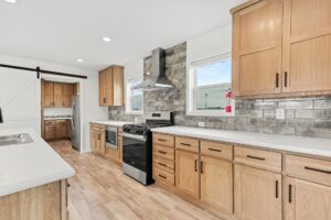 Kitchen with slate backsplash, range hood and oak cabinets in a new manufactured home at 4201 Shalimar Dr in Allendale, MI