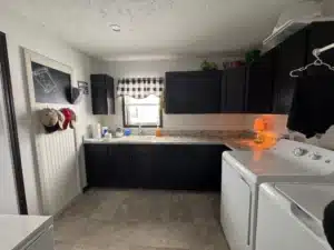 Kitchen with dark cabinets and laundry area in a pre-owned manufactured home at 4393 Twilight Way in Allendale, MI