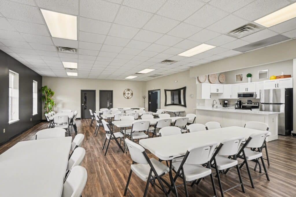Clubhouse gathering room with tables and kitchen at the manufactured home community in Allendale, MI