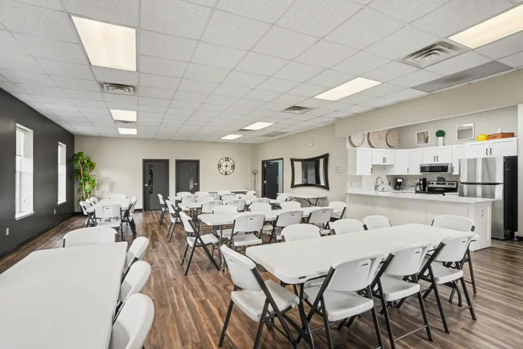Clubhouse gathering room with tables and kitchen at the manufactured home community in Allendale, MI