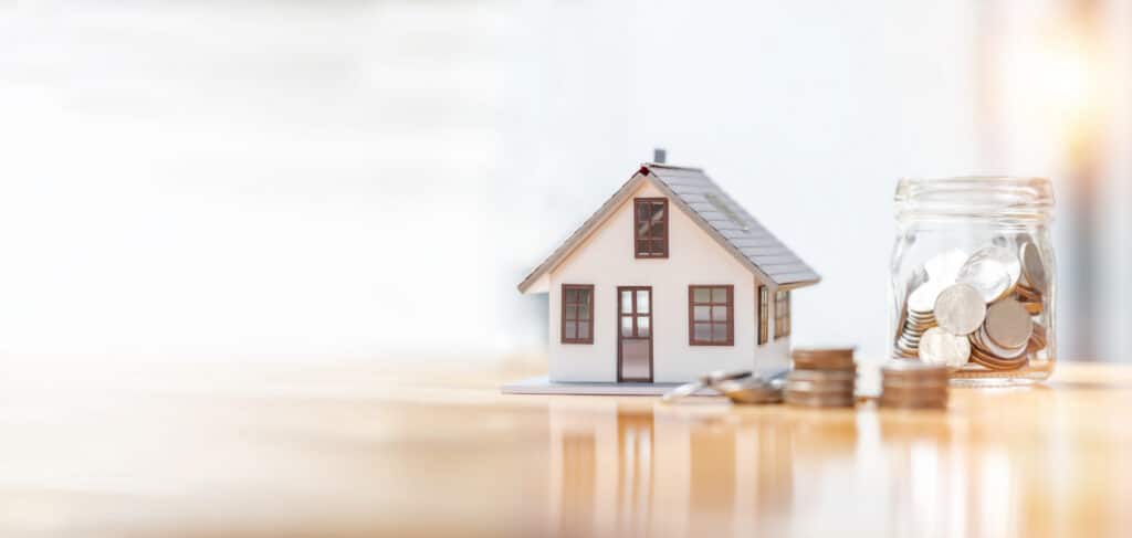 Model house beside a jar of coins representing manufactured home financing in Allendale, MI