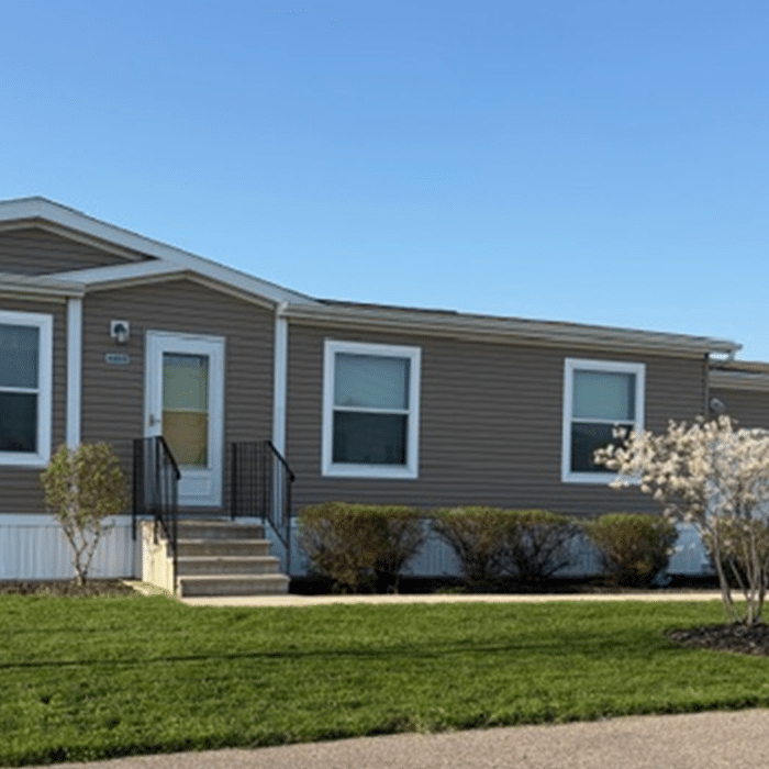 Pre-owned tan manufactured home with landscaped yard for sale in Allendale, MI