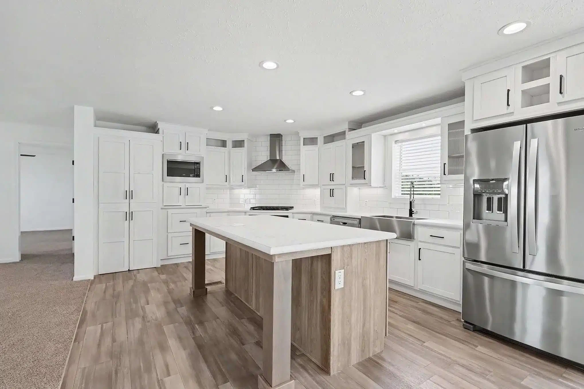 White kitchen with island, subway tile and stainless appliances in a new manufactured home
