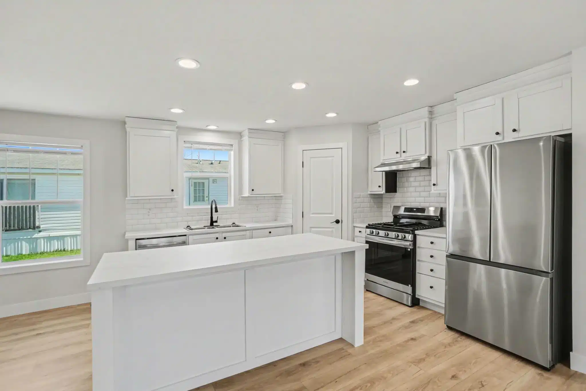 White kitchen with island, subway tile backsplash and stainless appliances in a pre-owned manufactured home in Allendale, MI