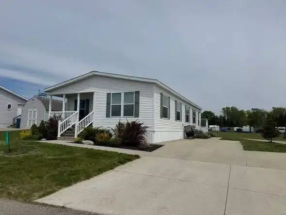 Pre-owned white manufactured home with covered front porch, landscaping and concrete driveway